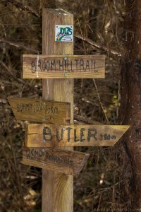 A wooden trail marker shows the distance