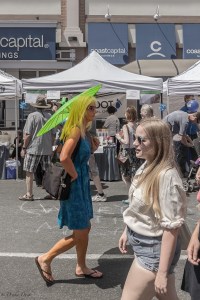 a woman with a bright green parasol walks on Douglas St