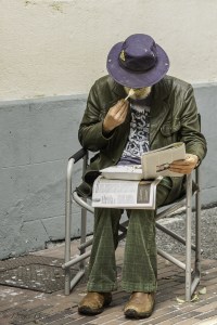 man eating lunch on his lap while reading the paper