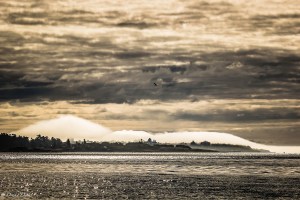 low fog rolls over land while high clouds darken the view