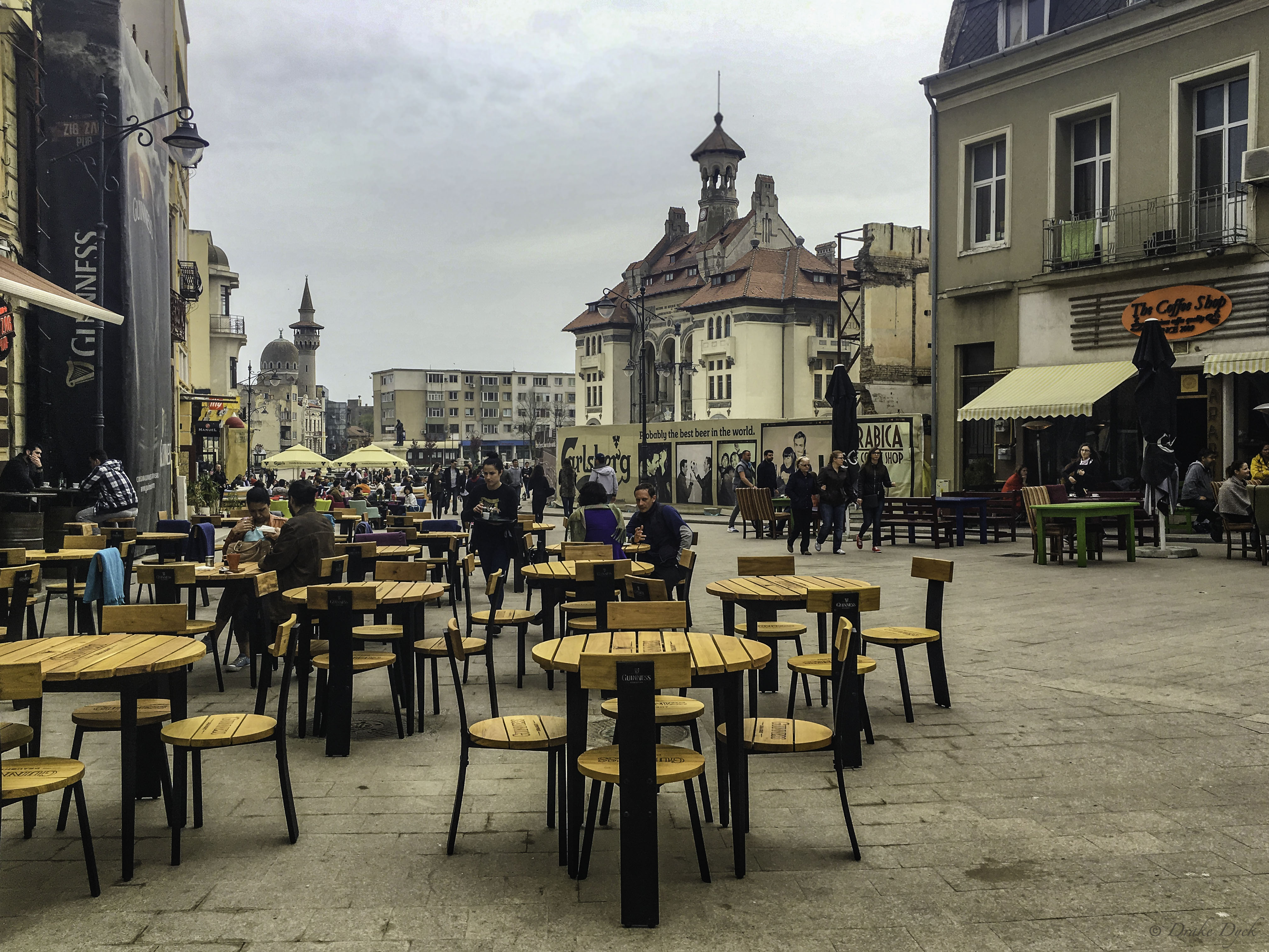 pedestrians, tables and shops line the street in Constanta Romania