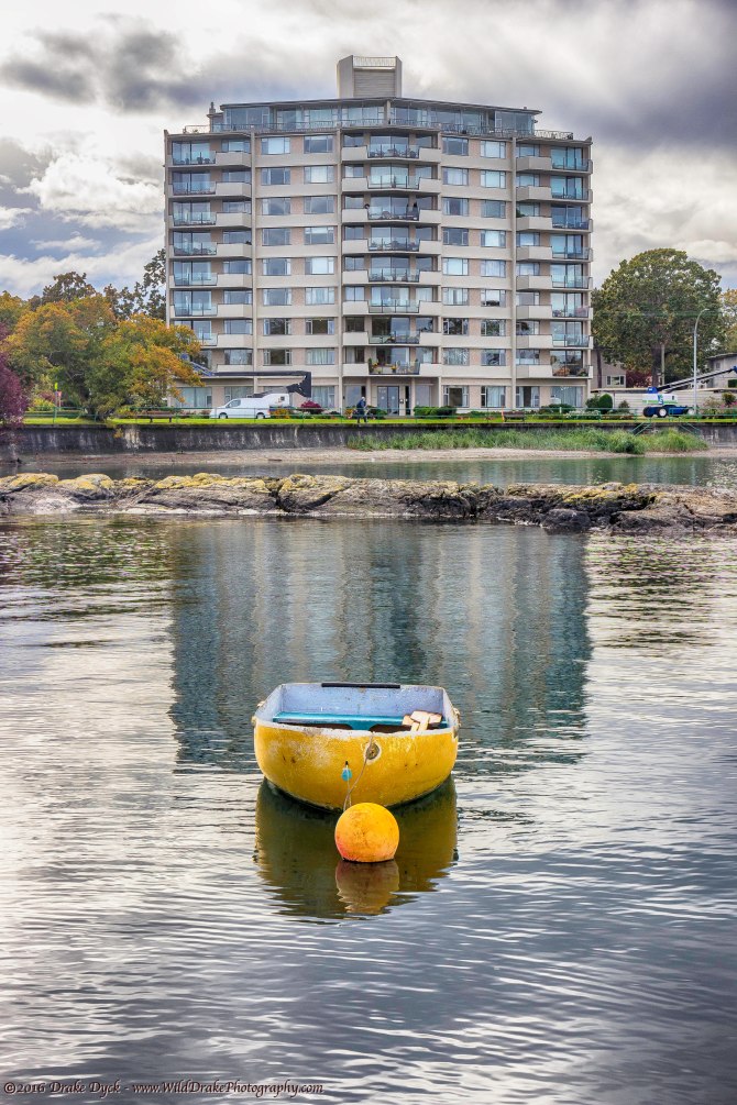 a yellow boat floats in front of an apartment building