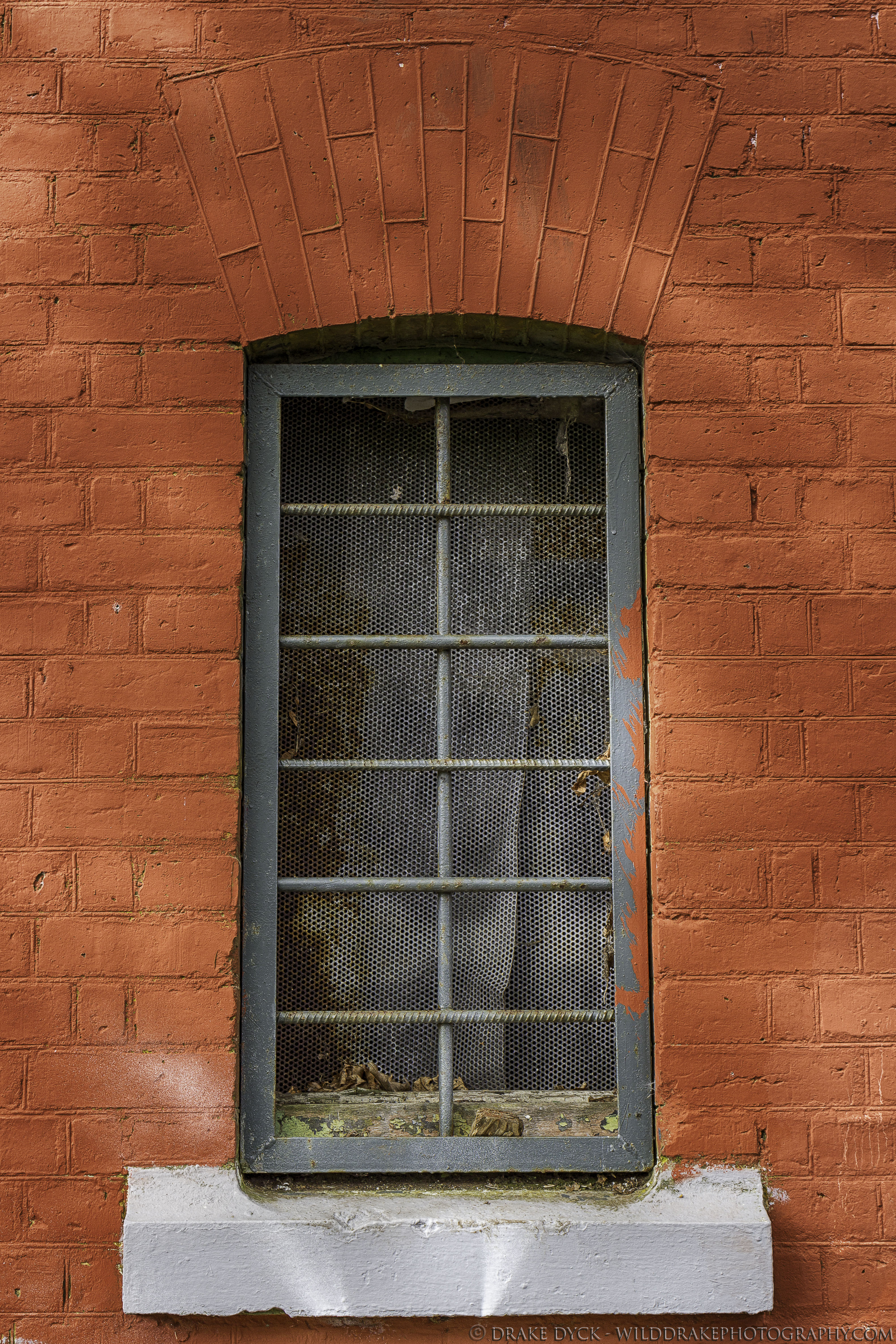 red painted brick and an iron bar window