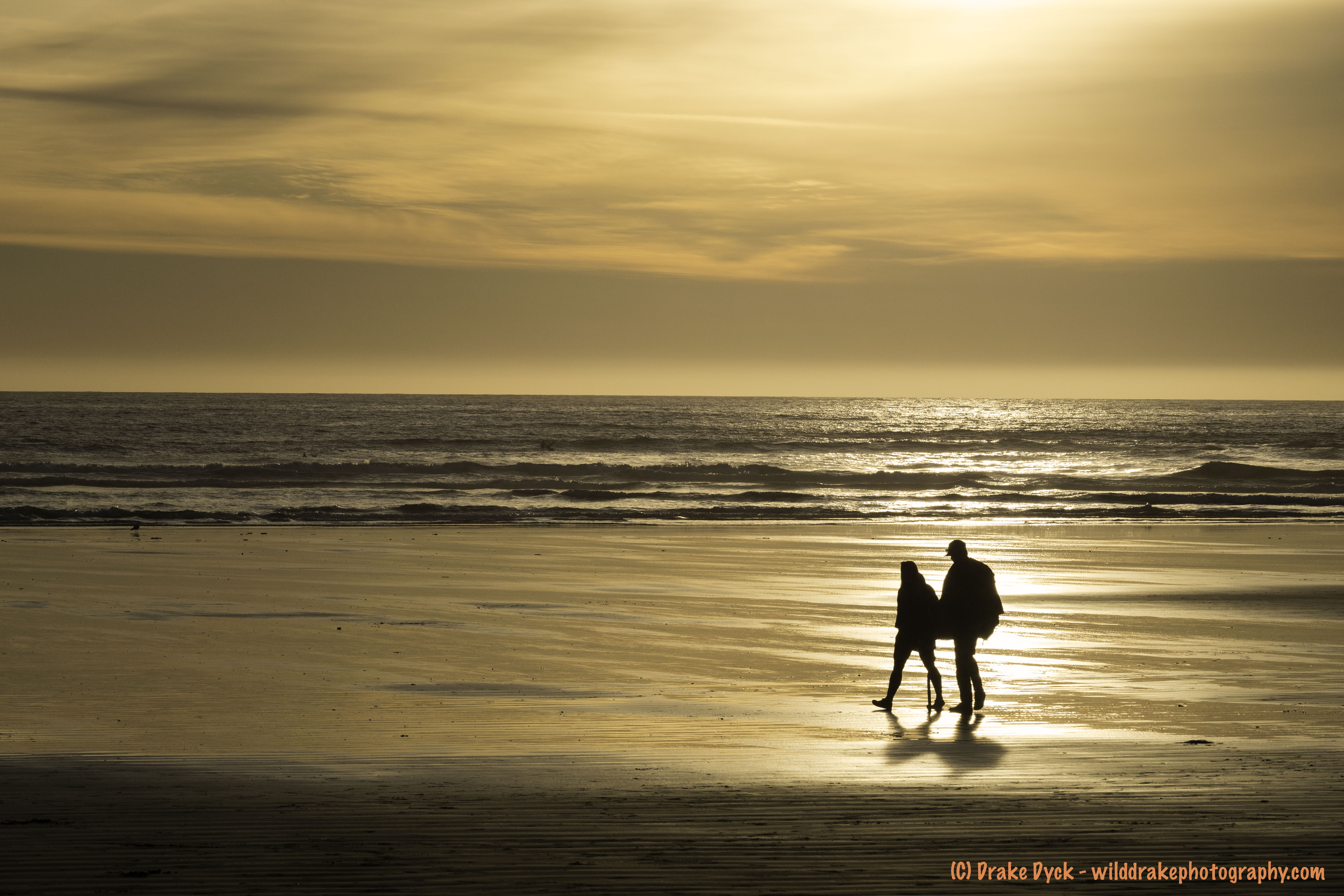 two people silhouetted in the reflection of a golden sunset