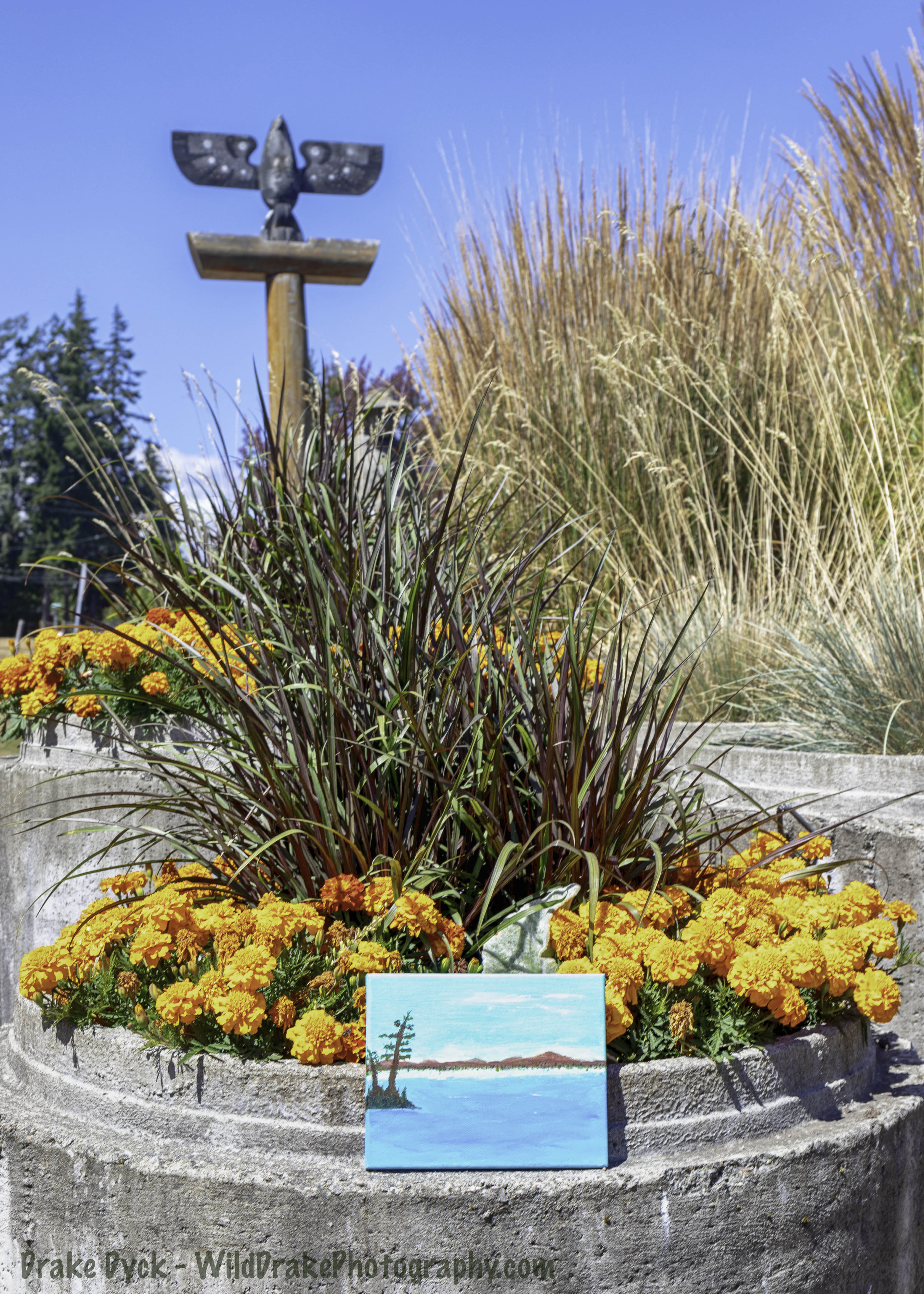 a small painting rests in front of a flower bed