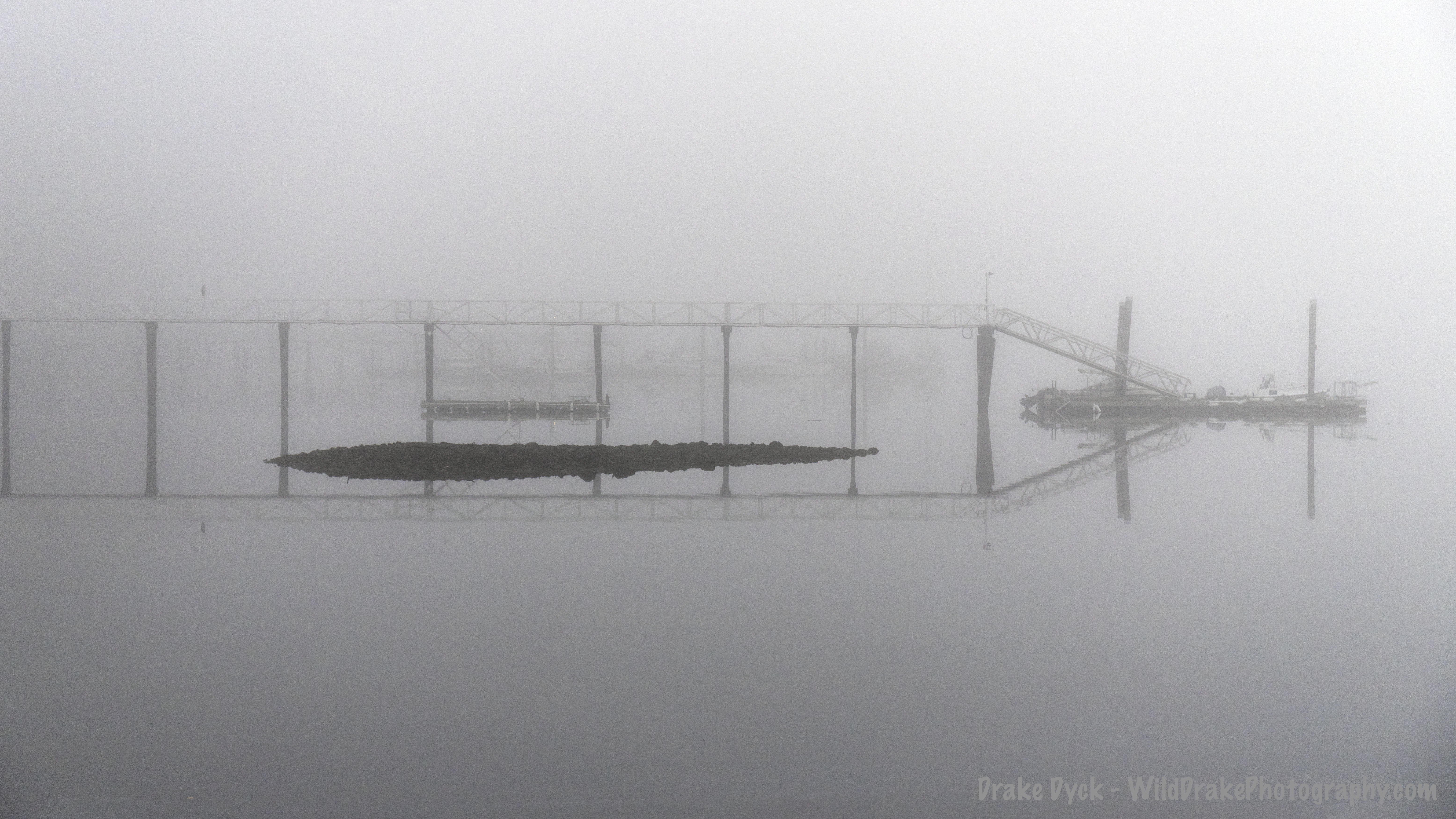 fog enshrouds a pier and rocks