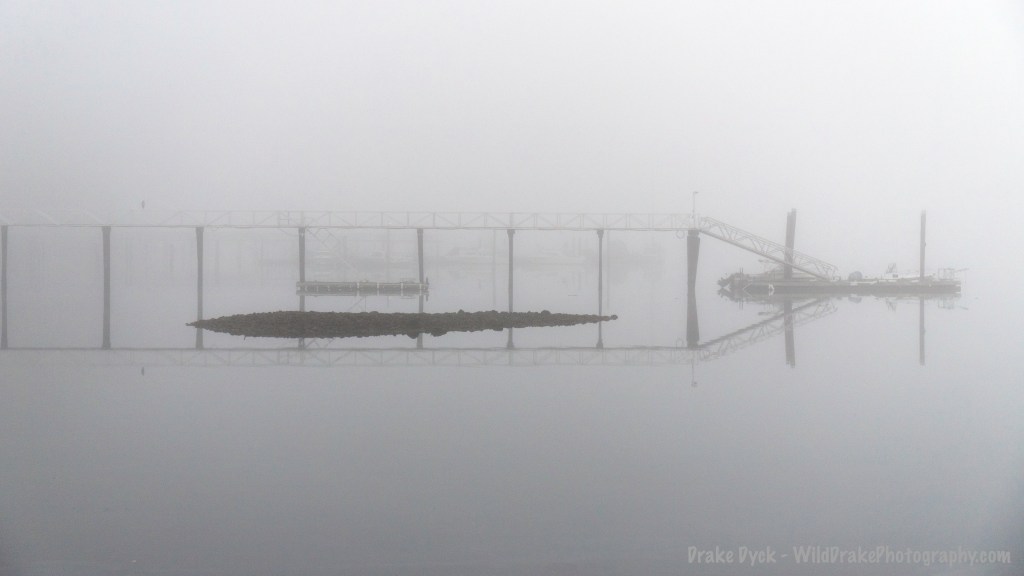 fog enshrouds a pier and rocks