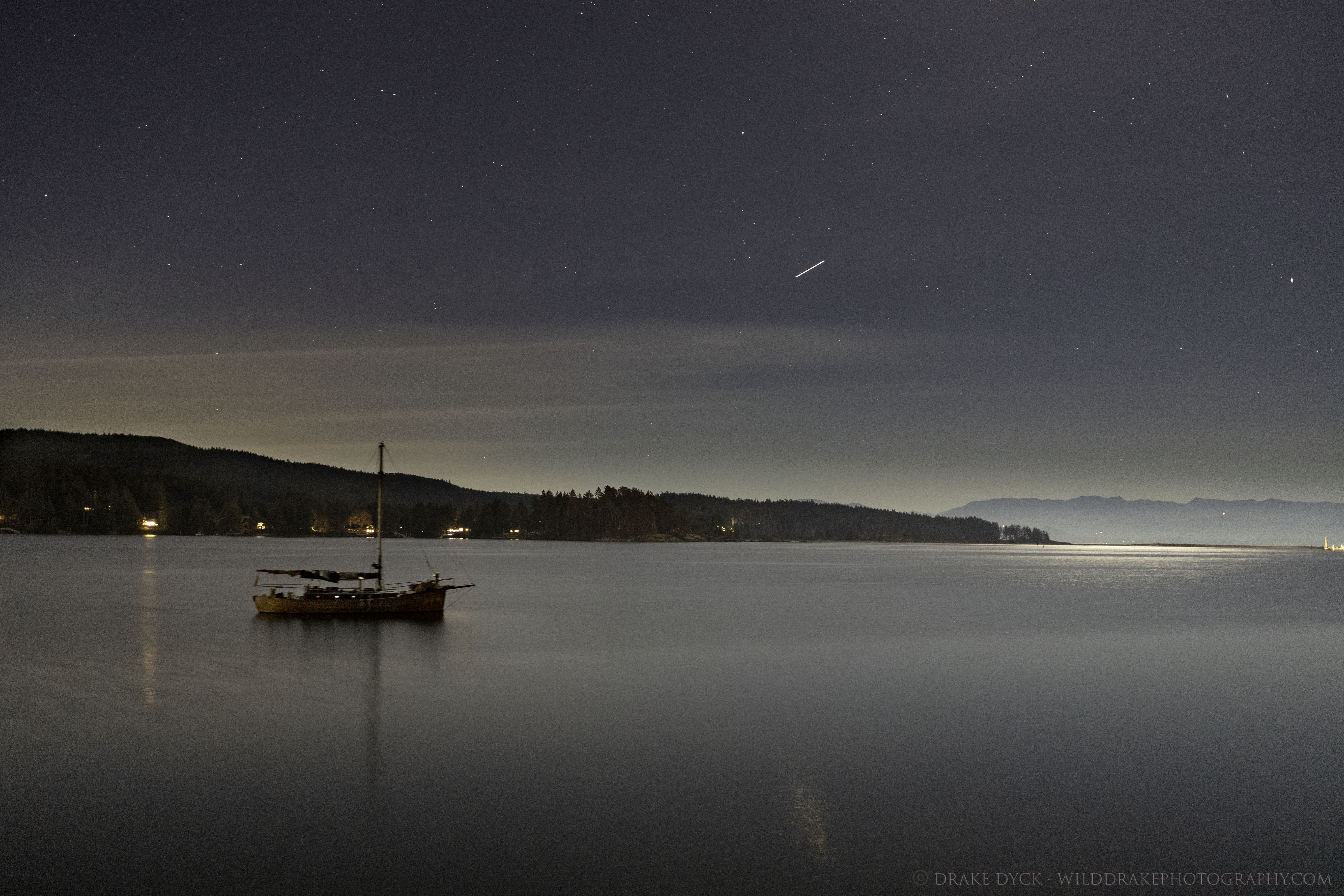 a meteorite can be seen streaking above a sailboat in the Sooke harbour
